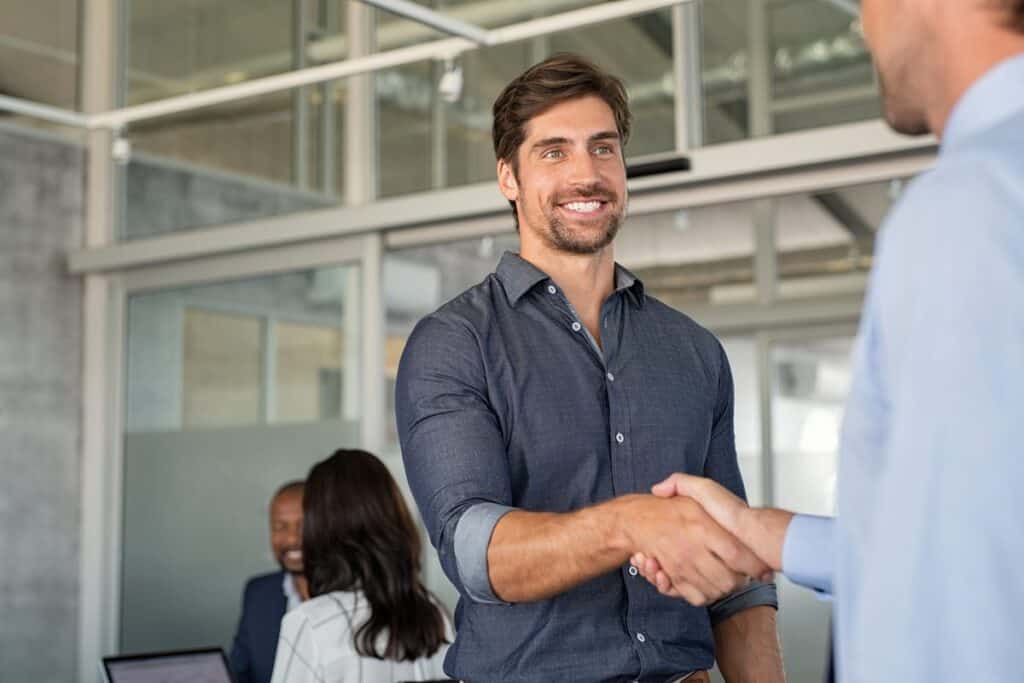 Sales professional shaking hands with a client in a modern office